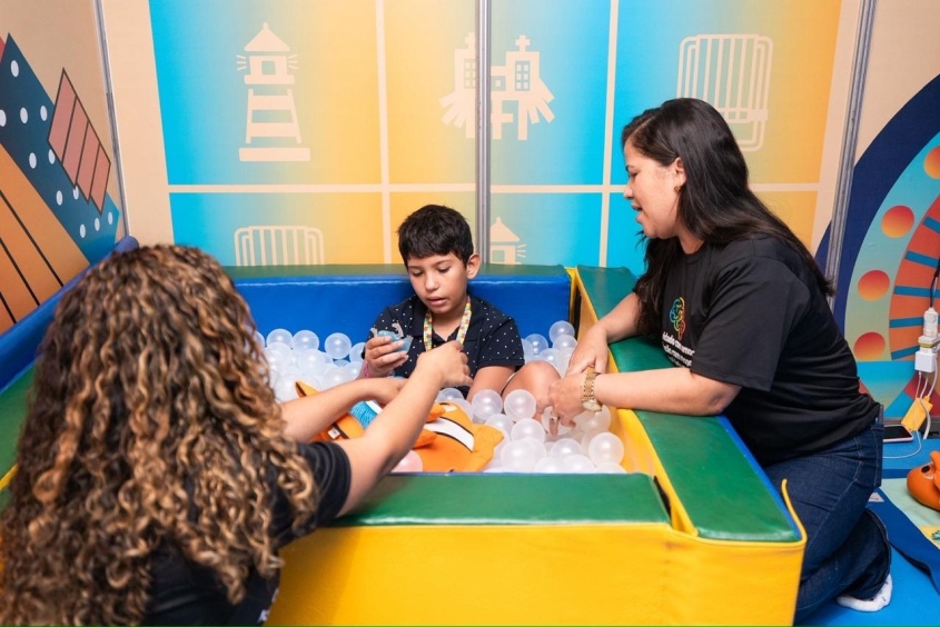 Criança recebe atendimento e estímulos com recursos sensoriais na piscina de bolinhas, um dos espaços montados para acolhimento e acomodação durante o evento. Foto: Victor Vercant/Secom Maceió